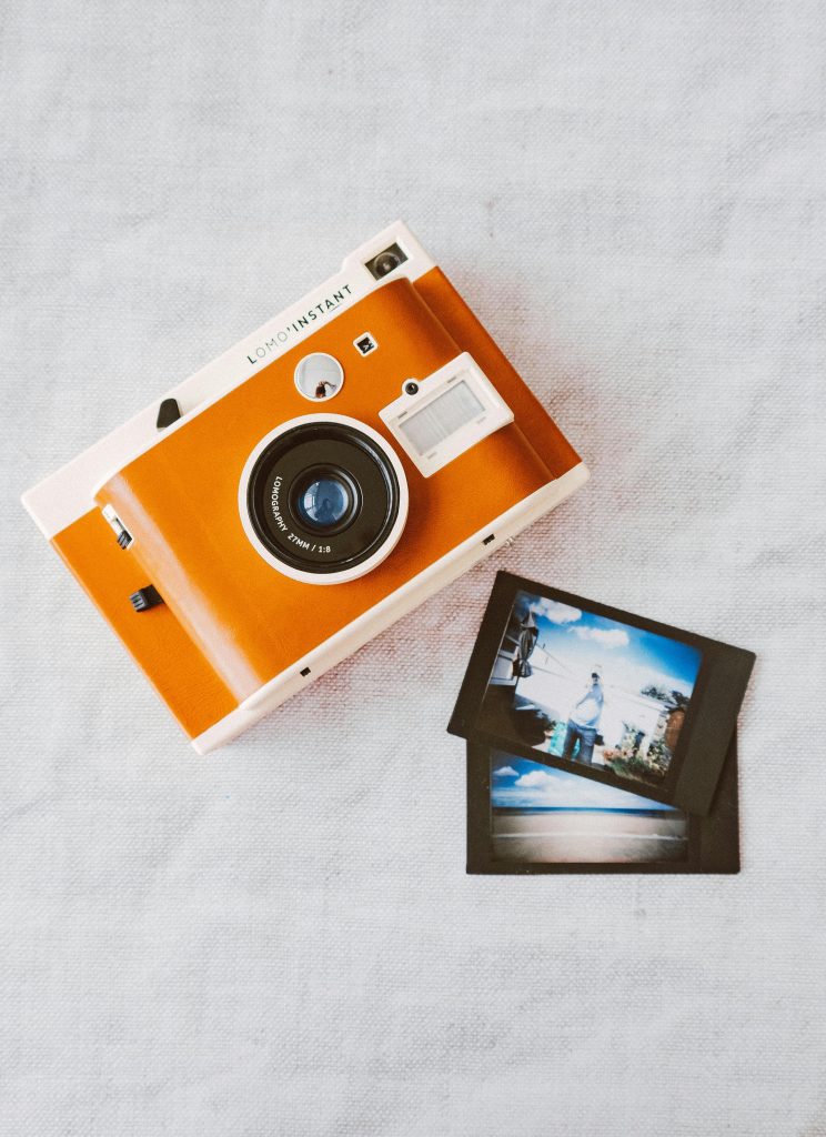 Top view of a vintage instant camera with developed photos on a textured surface.