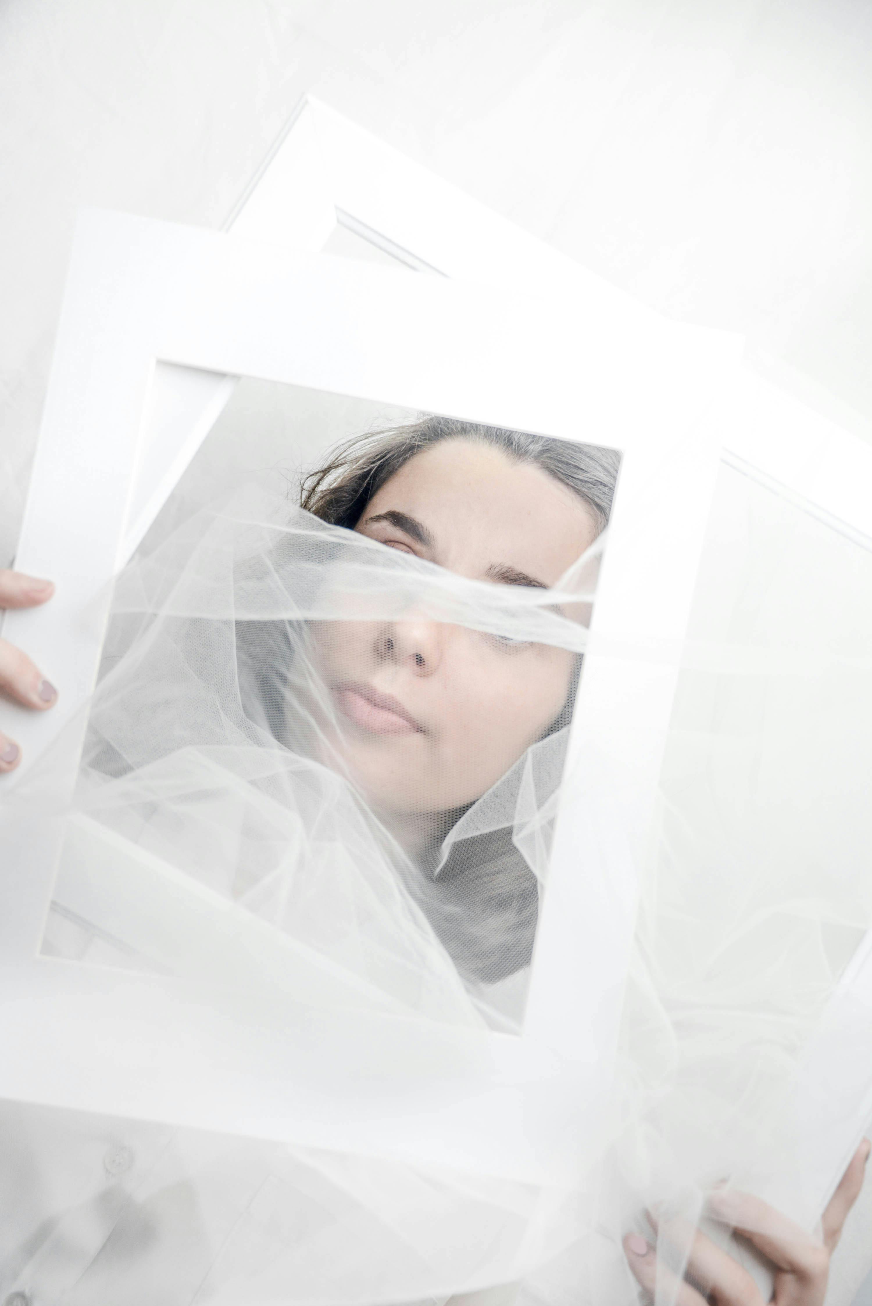 Artistic portrait of a woman with veil and frame, creating an ethereal effect.